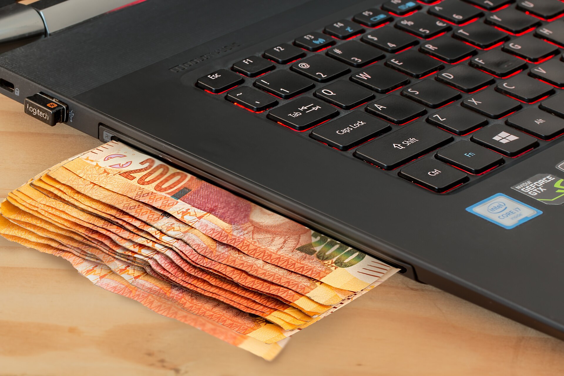 Cash and a laptop illustrating dollar-cost averaging through automatic online investing